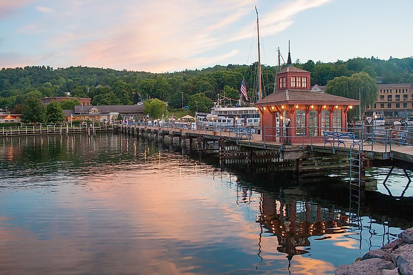 A peaceful pier extending into Seneca Lake in Watkins Glen, New York, with calm water reflecting the sky and surrounding landscape on a summer day.