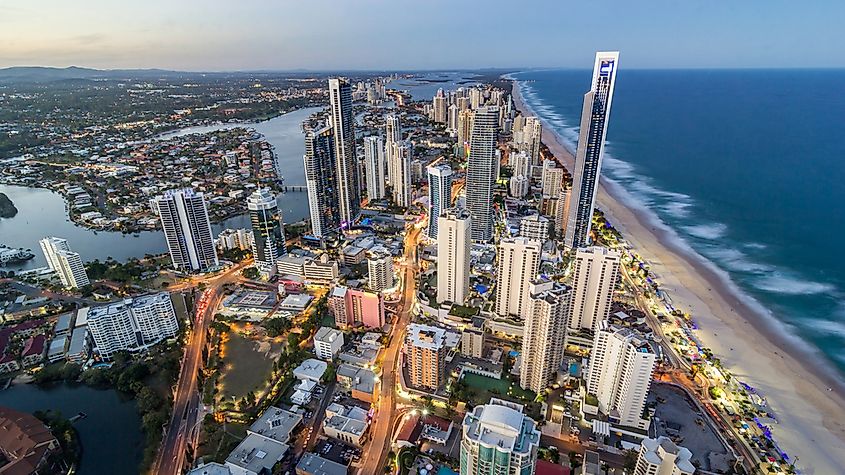 Rising sun shining on modern urban towers of Surfers paradise in Australian Gold Coast facing endless waves of Pacific ocean.