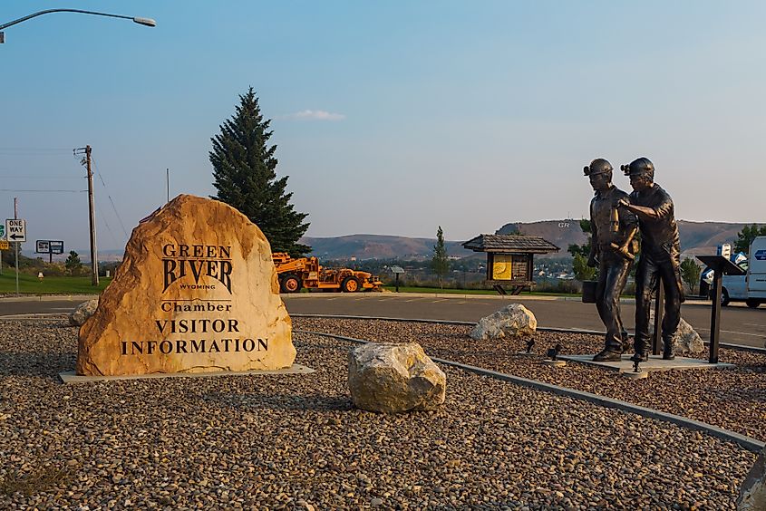 Statue of two miners, titled "Shift Change" by Bryan Cordova, and the Visitor Center sign at the parking lot in Green River, Wyoming, USA.