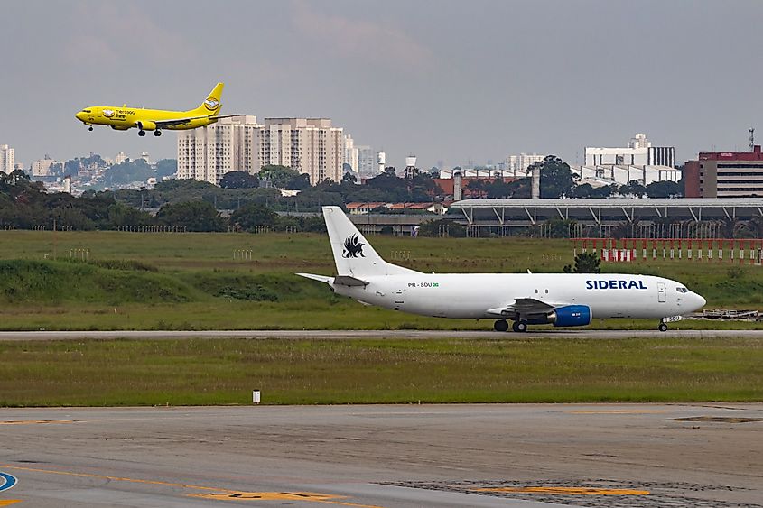 A Mercado Livre Boeing 737-800(F) lands at São Paulo International Airport as a Sideral Air Cargo Boeing 747-400(F) heads to the cargo terminal. Image Credit Ariadne Barroso via Shutterstock.