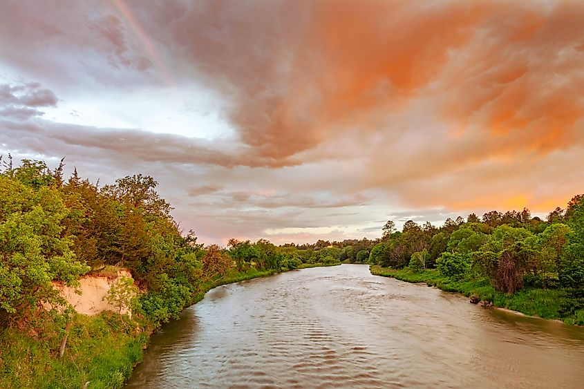 Colorful sunrise clouds reflect on the Niobrara River near Valentine, Nebraska.