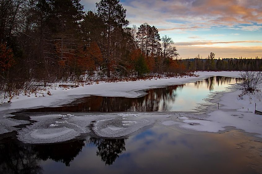 Sunset is approaching in Boulder Junction, Wisconsin.  The stream is covered with a thin layer of ice.