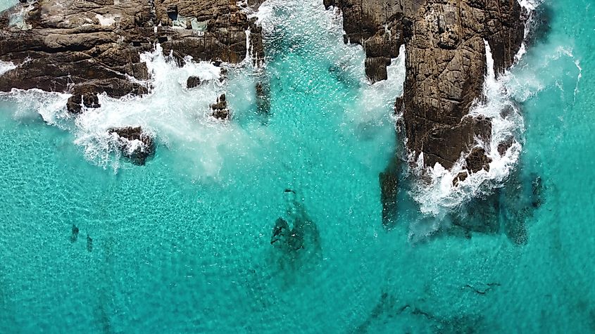 Aerial view of shallow blue water with rocks and small waves near Bremer Bay, in southwest Australia.