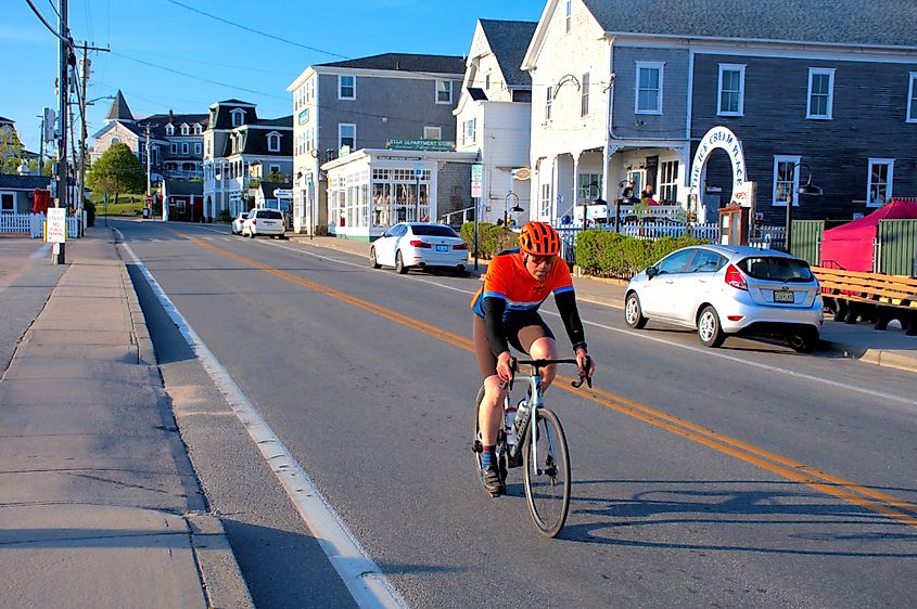 New Shoreham, Rhode Island, USA: Bicyclist takes an early morning ride past the harbor-side shops.