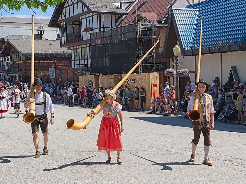 People dressed in traditional german clothes carry large alpenhorns during the Maifest celebration in Leavenworth, Washington. Editorial credit: Gregory Johnston / Shutterstock.com