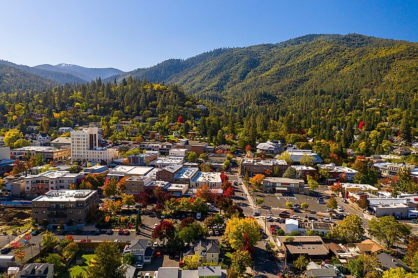 Aerial view of Ashland, Oregon, showcasing the town's scenic landscape with tree-lined streets, historic buildings, and the surrounding mountains.