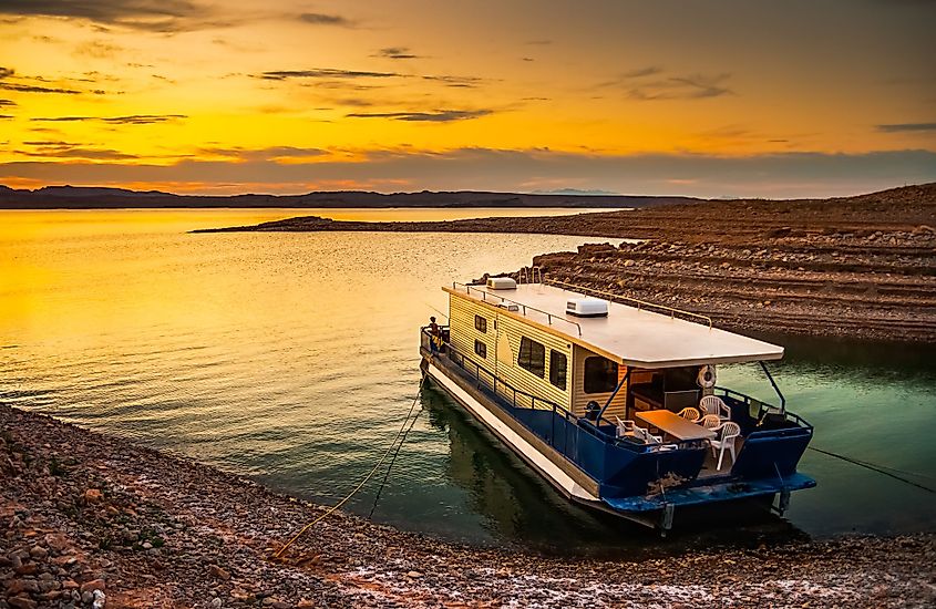 Beautiful scenic landscape of the Lake Mead National Recreation Area with a houseboat moored to the shores and a dramatic sky at sunset