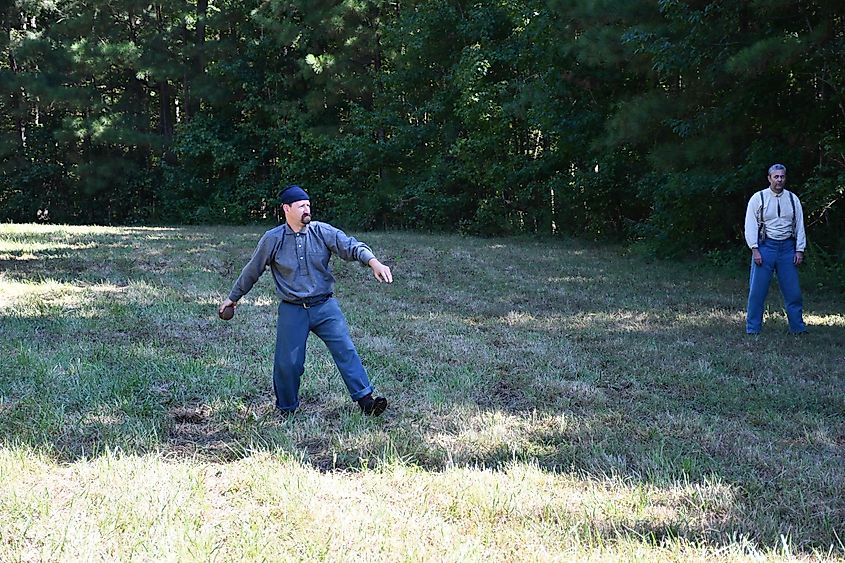 Living history volunteer portraying the 6th Wisconsin pitches a large leather ball underhand in a game of rounders at Petersburg National Battlefield