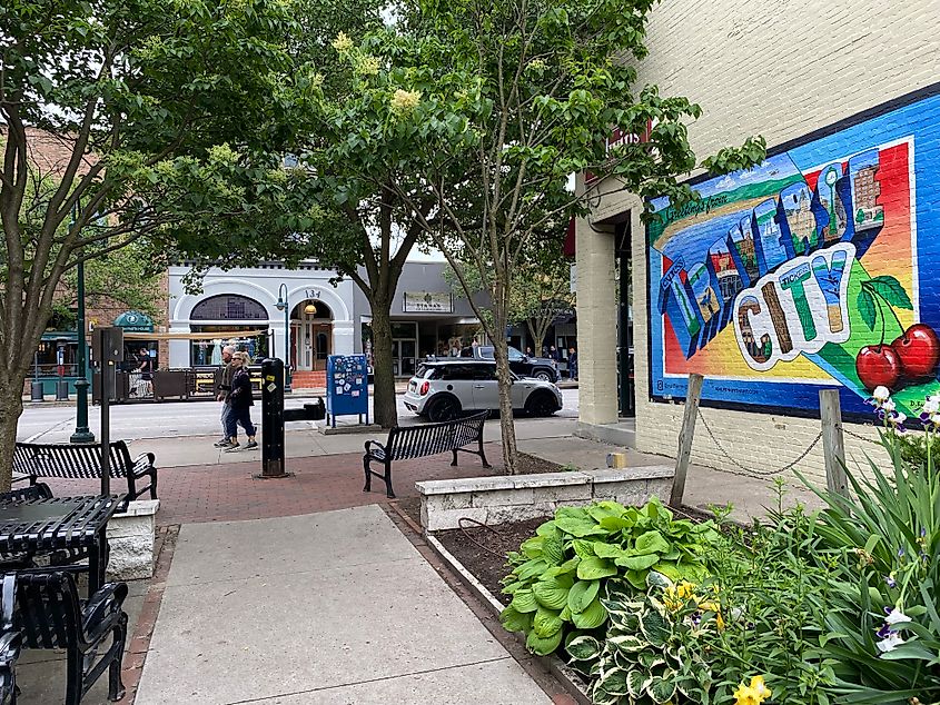 Another colorful town mural for Traverse City. A couple can be seen walking by, with background views of the shop-lined Front Street