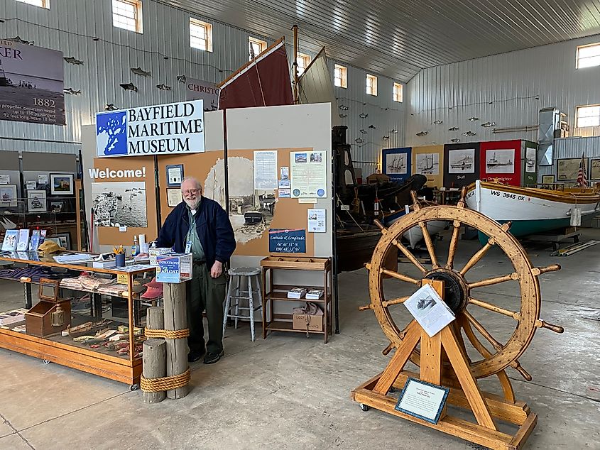 An old man stands ready to greet guests at the Bayfield Maritime Museum.