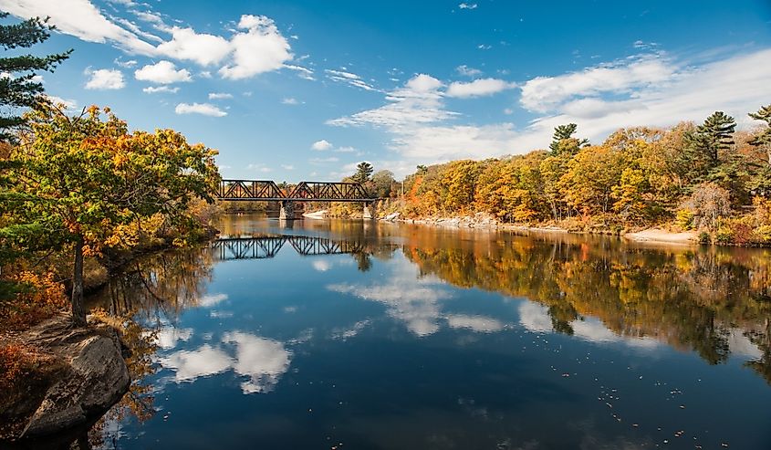 Railroad bridge over the Androscoggin River in Brunswick, Maine, with fall foliage.