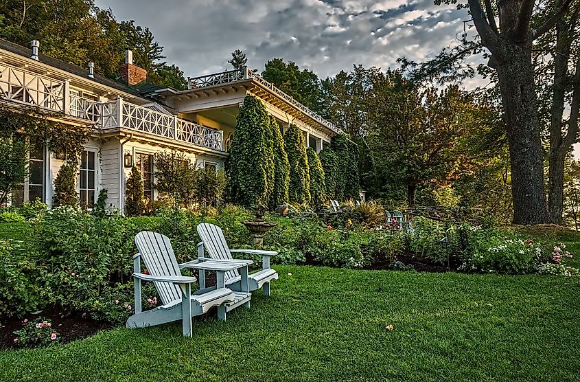  The lakeside gardens of a historic inn in Quebec's Eastern Townships at sunrise with Adirondack style chairs and 19th century architecture. Editorial credit: ezjay / Shutterstock.com