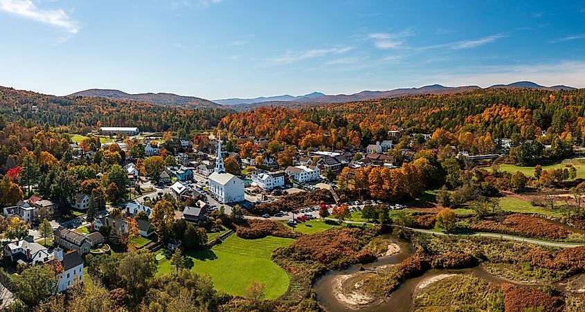Panoramic aerial view of Stowe, Vermont, during fall, highlighting the vibrant autumn foliage and scenic landscape surrounding the town.
