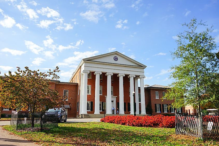 A building on the University of Mississippi campus in Oxford, MS, featuring classic Southern architecture with brick facades and tall columns, surrounded by manicured lawns and trees.