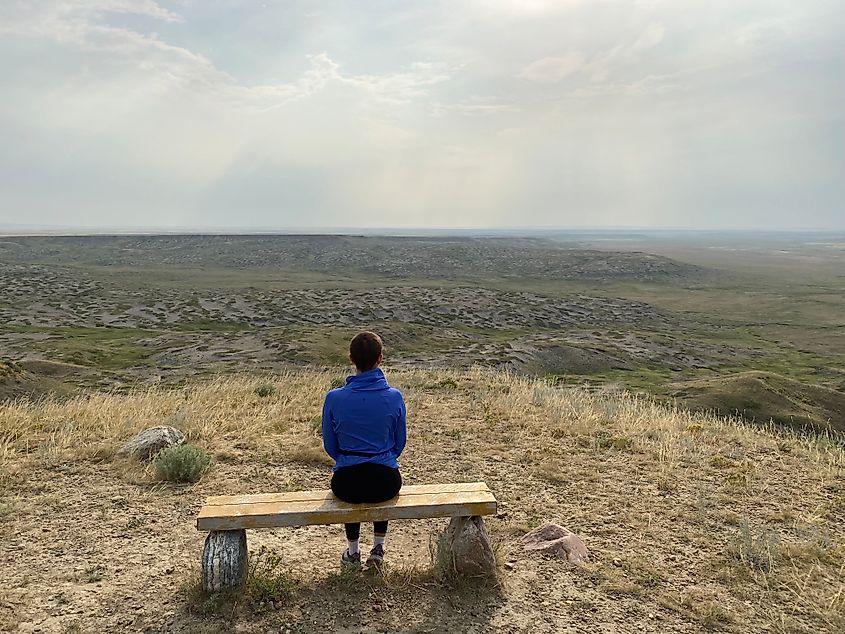 A young woman sits at a viewpoint bench above Saskatchewan's sprawling grasslands 