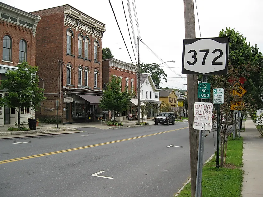 New York State Route 372 heading eastbound in the village of Greenwich, NY, with a clear roadway and surrounding buildings.