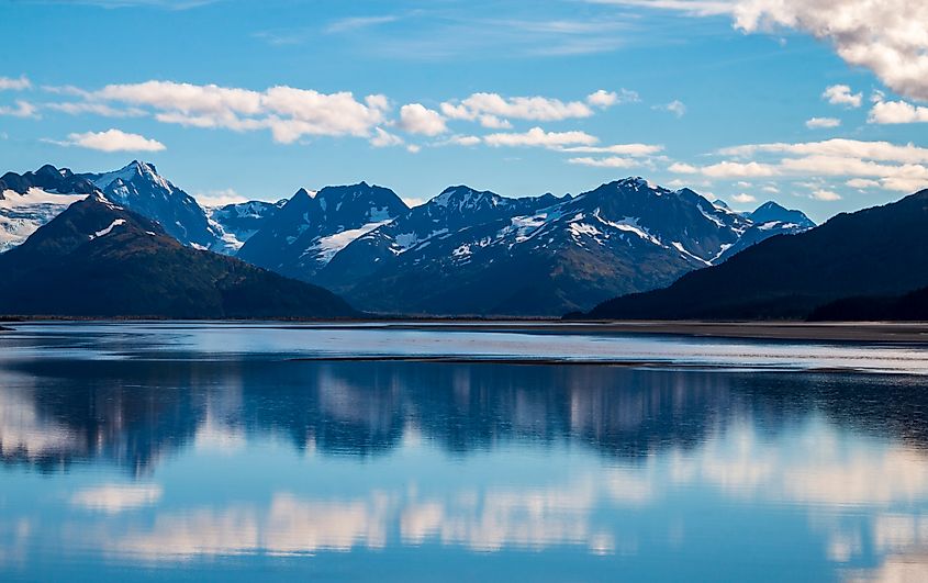 calm waters of Cook inlet near Anchorage, Alaska w snow capped mountains on the background.