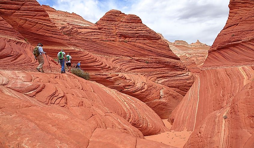 Hiker descending into a red sandstone canyon beneath The Wave, Paria Canyon, Vermilion Cliffs Wildnerness Area, Kanab, Utah