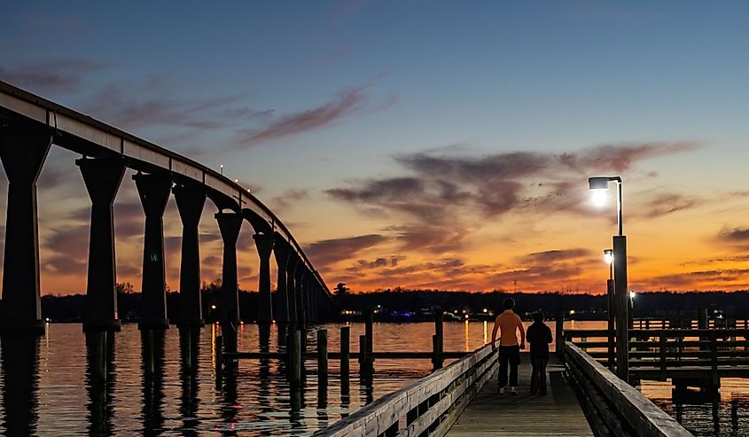 A young couple on a pier below the the Solomons Bridge at night, or Gov. Thomas Johnson Bridge