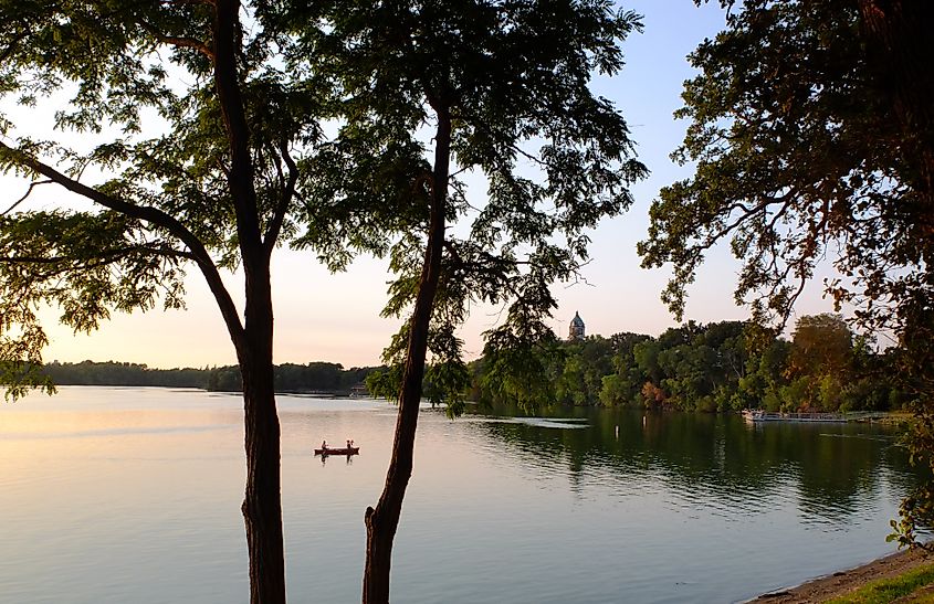 A couple and their dog paddle across the calm waters of Hall Lake at sunset in Fairmont, Minnesota