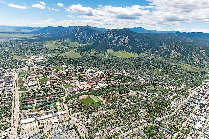Aerial view of Boulder's suburbs nestled amongst hills and blue skies.