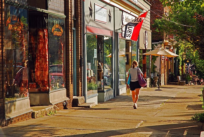 A young woman walks past independent stores and boutiques on a sunny day in Cold Spring, New York.