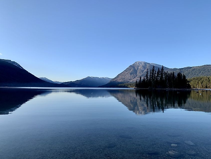 Clear blue sky over the pristine waters of Lake Wenatchee, Washington State, with surrounding mountains and forests enhancing the scenic view.