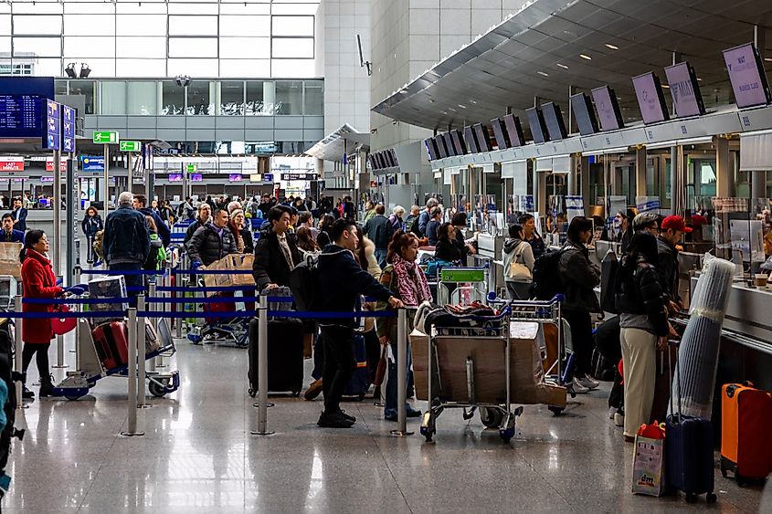 Travelers waiting at the check-in counter at Frankfurt Airport, Germany. Image Credit Jokue-photography via Shutterstock.