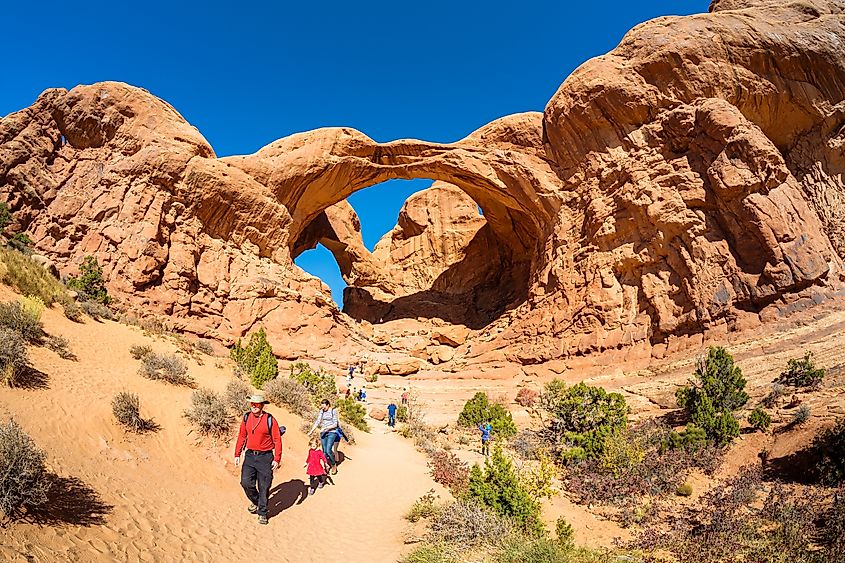 Tourists enjoying the natural beauty of the Double Arch in Arches National Park, Moab, Utah