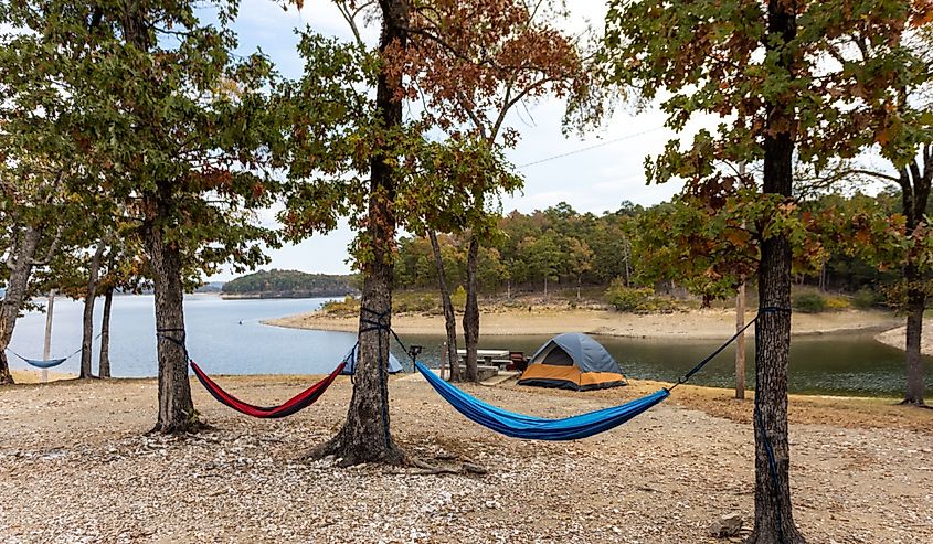 Camping tents and hammock near a beautiful lake among trees, campsite, adventure vacation concept, Broken bow lake in Oklahoma, USA.