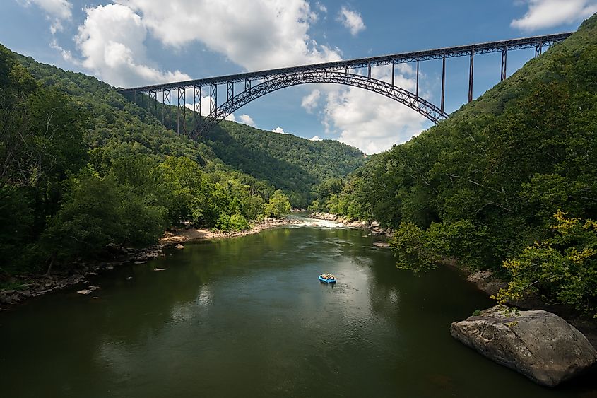 Rafters float towards the rapids under the high arched New River Gorge bridge in West Virginia.