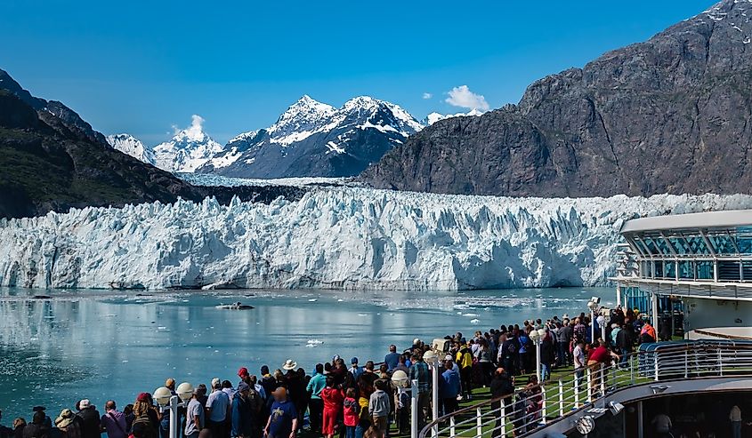 A group of tourists are enjoying the gorgeous view of the Margerie Glacier in the Glacier Bay of Alaska on a sunny day.