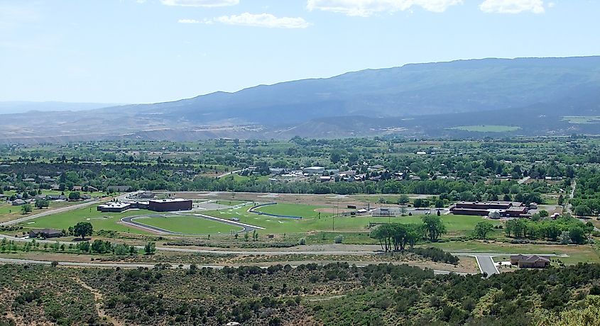 The town of Cedaredge, Colorado, viewed from Cedar Mesa, with Cedaredge High School and Middle School in the foreground and a backdrop of rolling hills and open landscape.