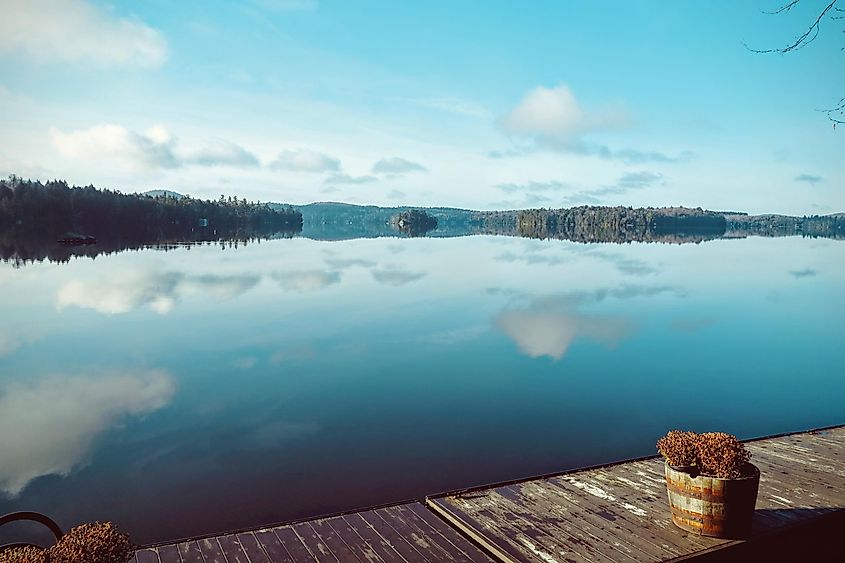 Amazing scenery by the lake during morning in Tupper Lake. The forest and the sky in the background are reflected from the still water.