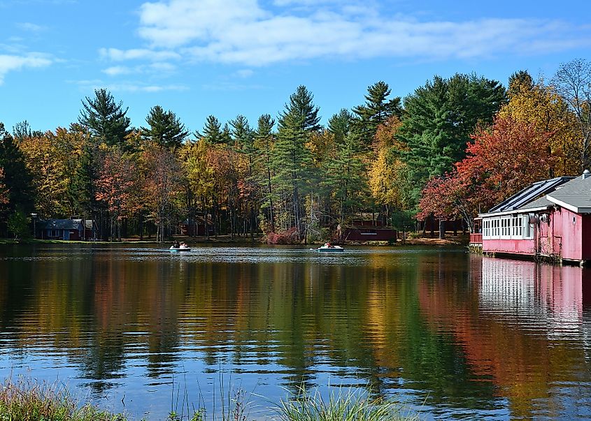 Cresco, Pennsylvania - October 13th 2013 - A peaceful lake surrounded by vibrant autumn trees, with paddle boats gliding near a charming red lakeside building