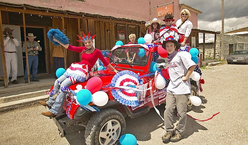 Teenagers riding a jeep decorated for the Fourth of July, in Lima, Montana.