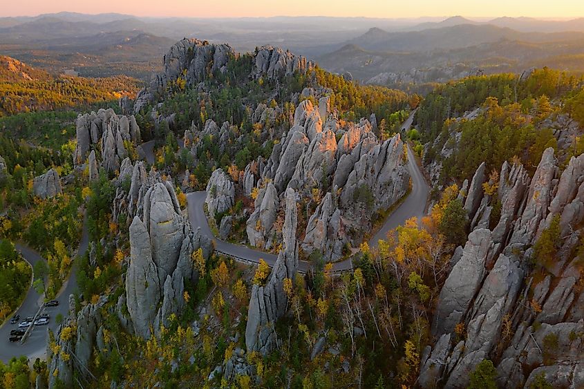 Aerial view of Needles Highway winding through the rugged granite spires of Custer State Park during autumn