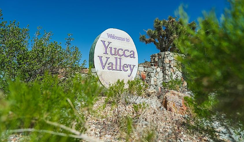 Yucca Valley welcome sign among the green trees