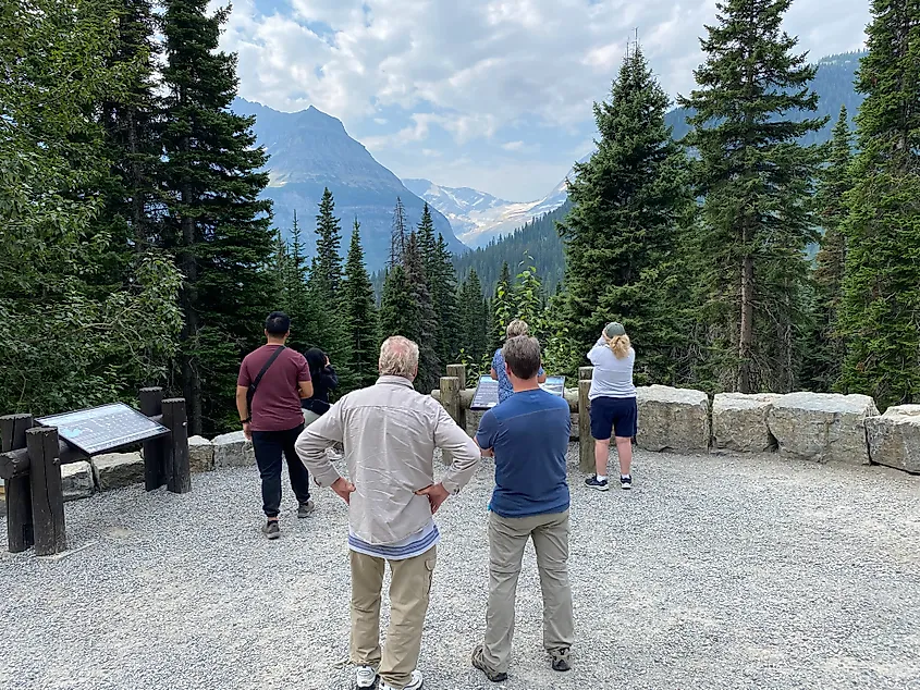 A group of people stop to admire a distant mountain glacier along the Going-to-the-Sun Road.