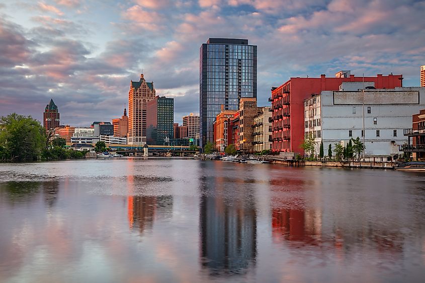 Cityscape image of downtown Milwaukee, Wisconsin, USA with reflection of the skyline in Mnemonee River at summer sunset.