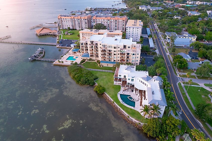 Aerial view of downtown Dunedin, Florida, in the Tampa Bay area, showcasing residential houses with pools, roads for cars, and the city's proximity to the Gulf of Mexico. A popular summer vacation destination.