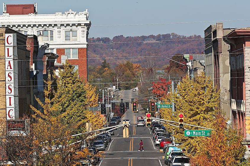 Small-town autumn street scene with colorful trees lining both sides. A theater with "Classic" sign is on the left. Clear sky, calm atmosphere.