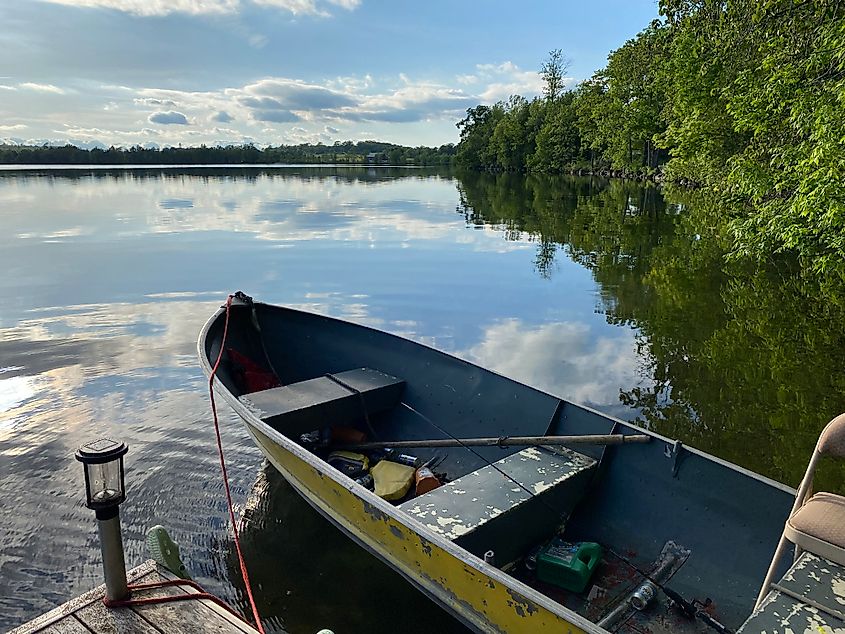 A rustic yellow motorboat parked at a dock on a small, forested lake