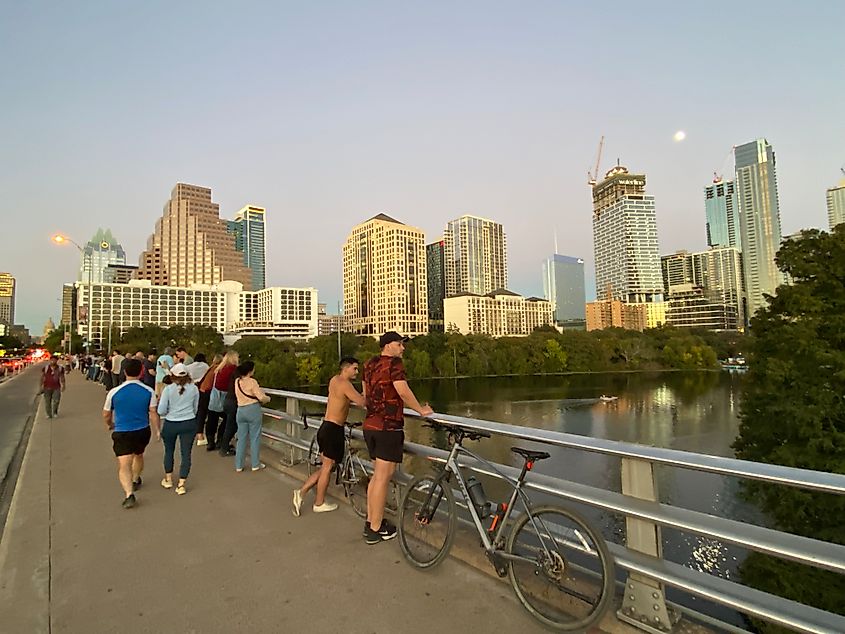 People line Austin's South Congress Bridge to watch the sun set and moon rise over the city's expanding skyline