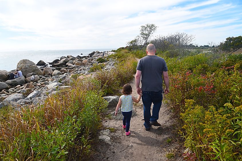 A man walks with his daughter along the coast at Hammonasset Beach State Park in Madison, Connecticut.