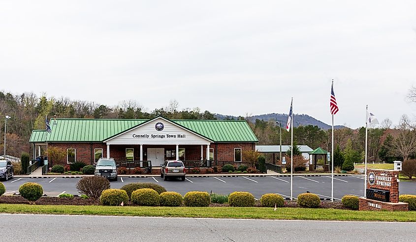 Town Hall building, parking lot, flags, poles, and monument sign at roadside in Connelly Springs, North Carolina.