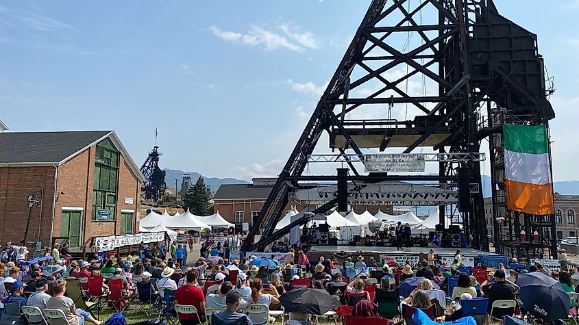 An oil derrick with a large Irish flag stands before a large festival crowd in Butte, Montana.