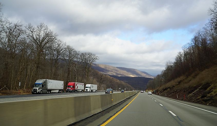 Transport trucks on the Pennsylvania Turnpike (Highway Life) with mountains in the background.