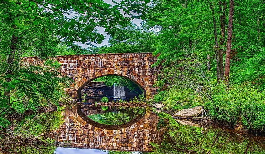 Bridge, waterfall and foliage reflections of scenic Davies Bridge in Petit Jean State Park near Russellville AR