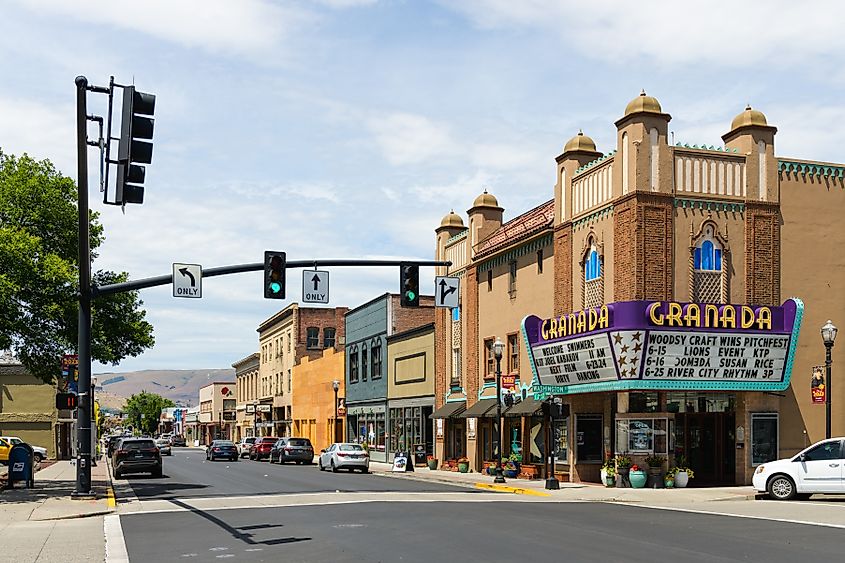 View along E 2nd Street in The Dalles, Oregon, featuring the historic Granada Theatre with its classic marquee, surrounded by a mix of small shops and buildings in the downtown area.